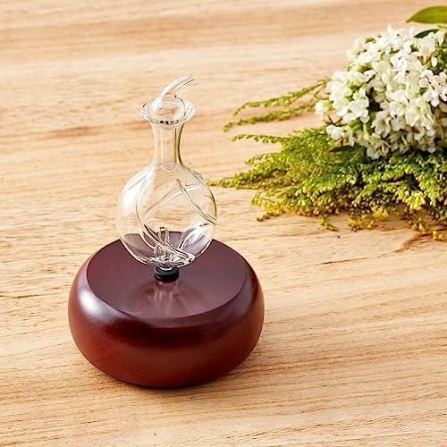 Diffuseur en verre sur base en bois avec fleurs blanches.