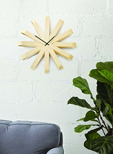 Horloge murale moderne en bois au-dessus d'un canapé avec plante verte.