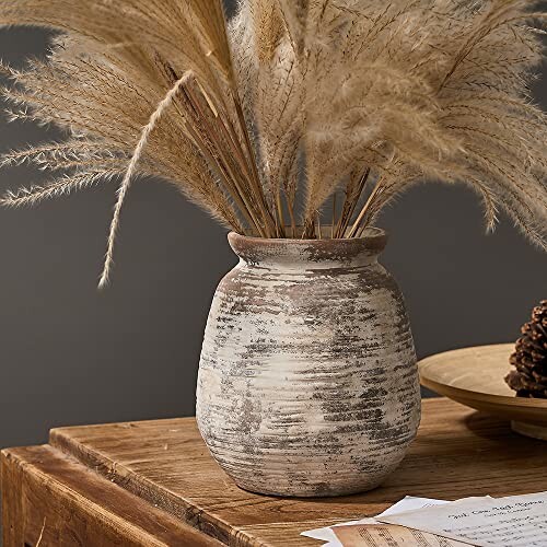 Vase rustique avec des herbes de la pampa sur une table en bois.