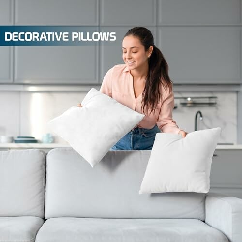 Femme organisant des coussins décoratifs sur un canapé gris.